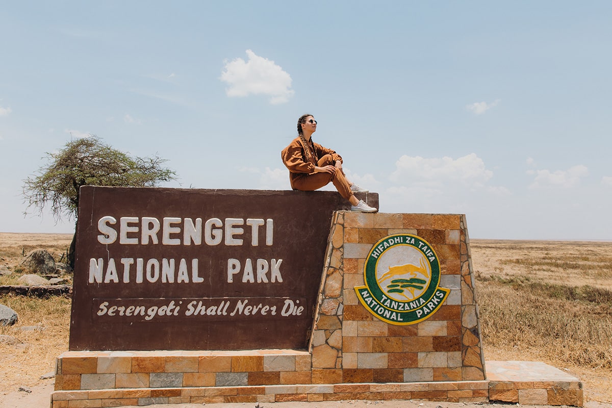 A-young-woman-sitting-on-the-stone-signboard-of-Serengeti-National-Park-Tanzania.jpg